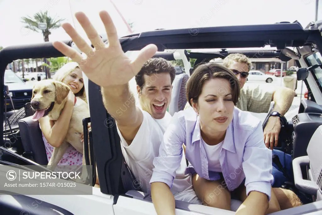Close-up of two young couples sitting in a jeep