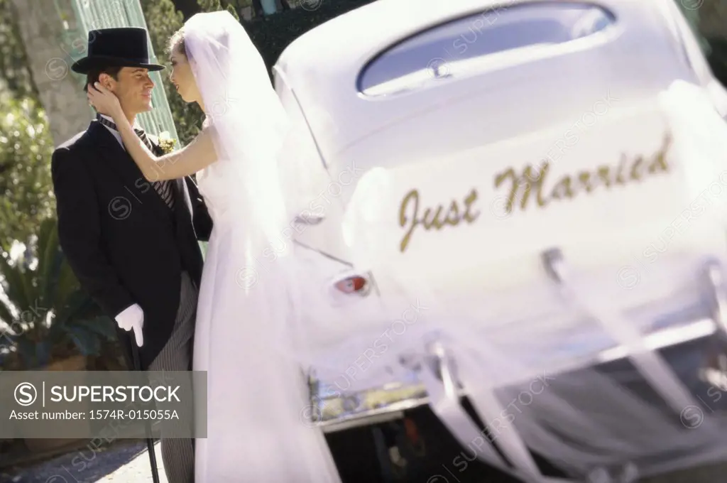 Side profile of a newlywed couple standing beside a car