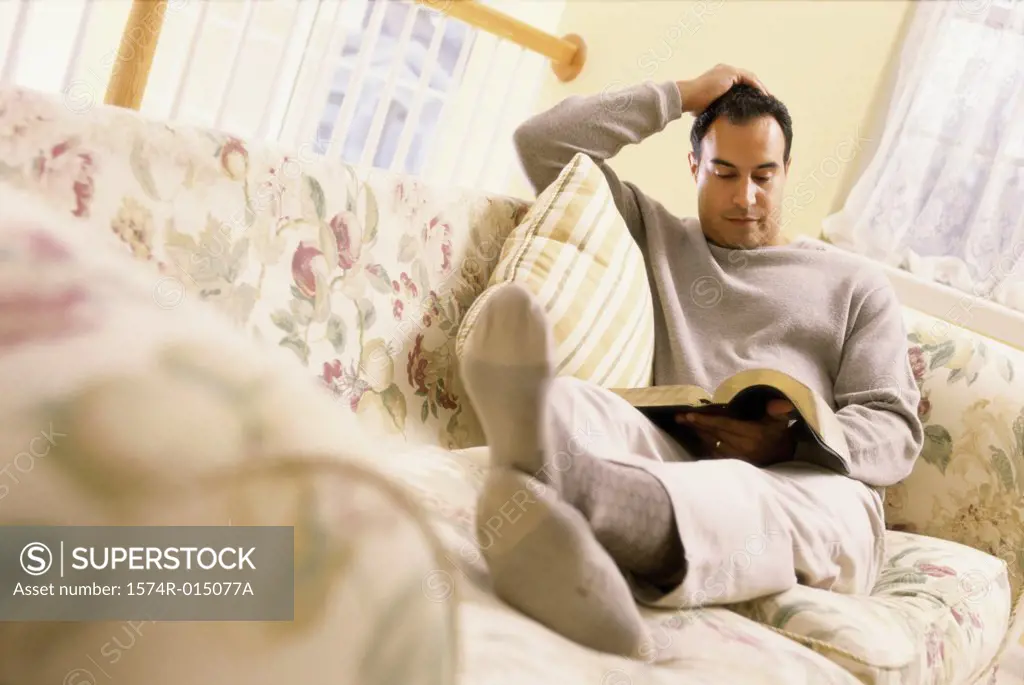 Mid adult man sitting on a couch reading a book