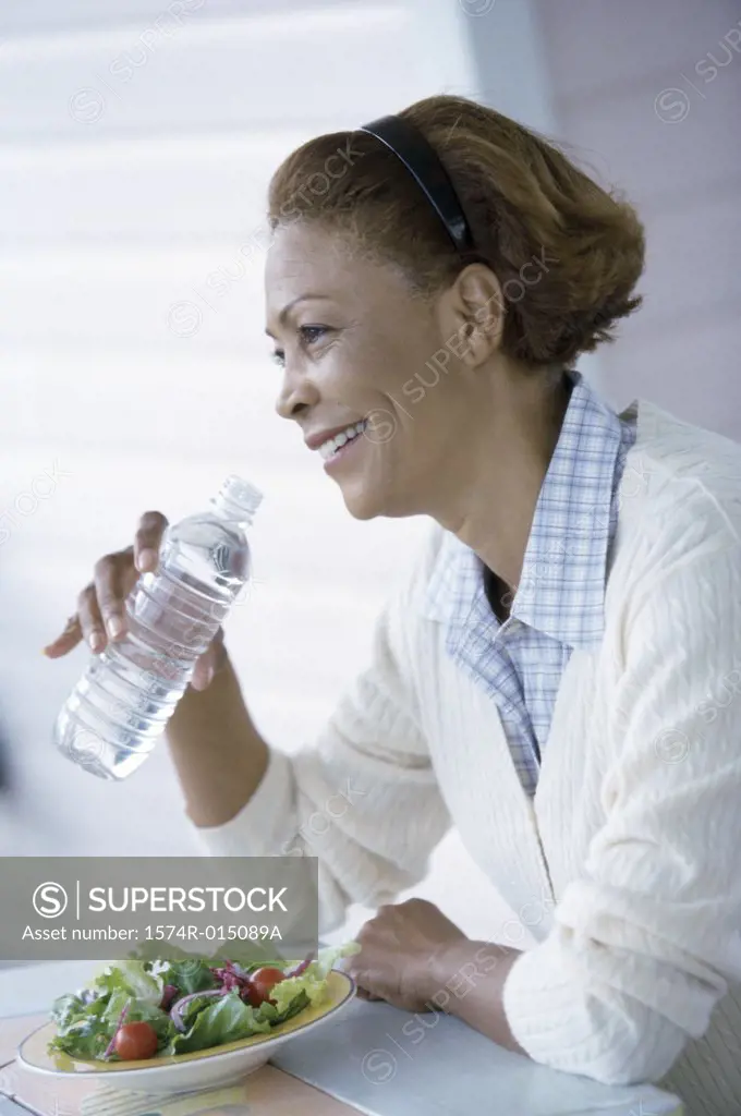 Side profile of a mid adult woman drinking water from a water bottle