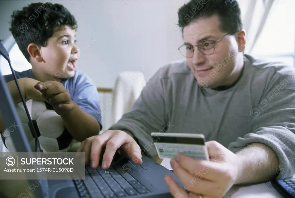 Close-up of a father and son sitting in front of a laptop