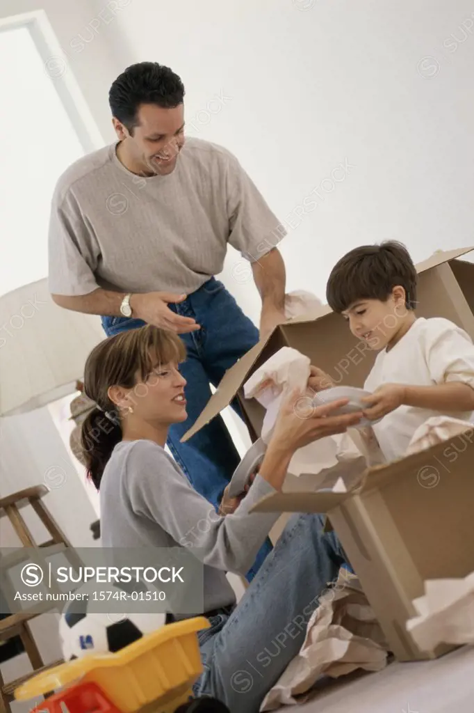 Young couple unpacking boxes with their son 