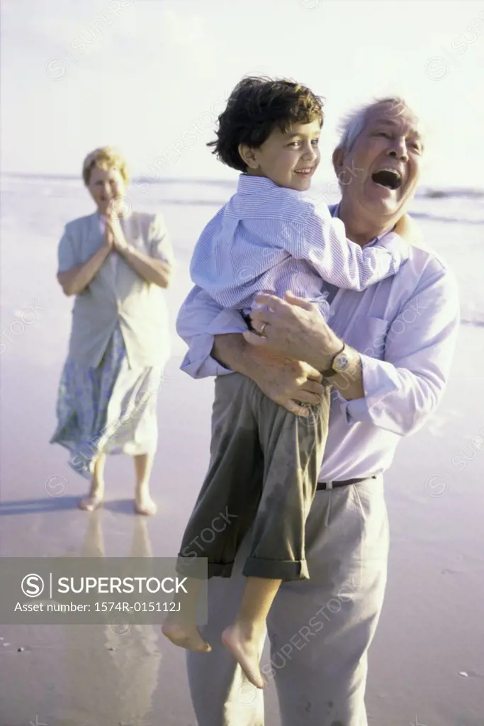 Grandfather carrying his grandson on the beach