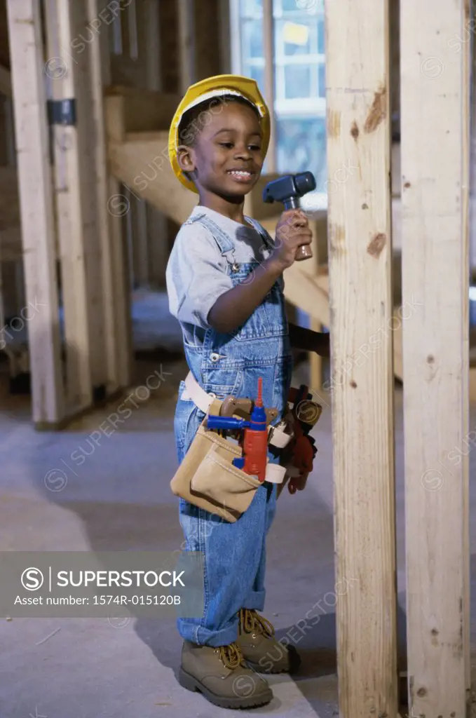Boy dressed as a construction worker holding a toy hammer