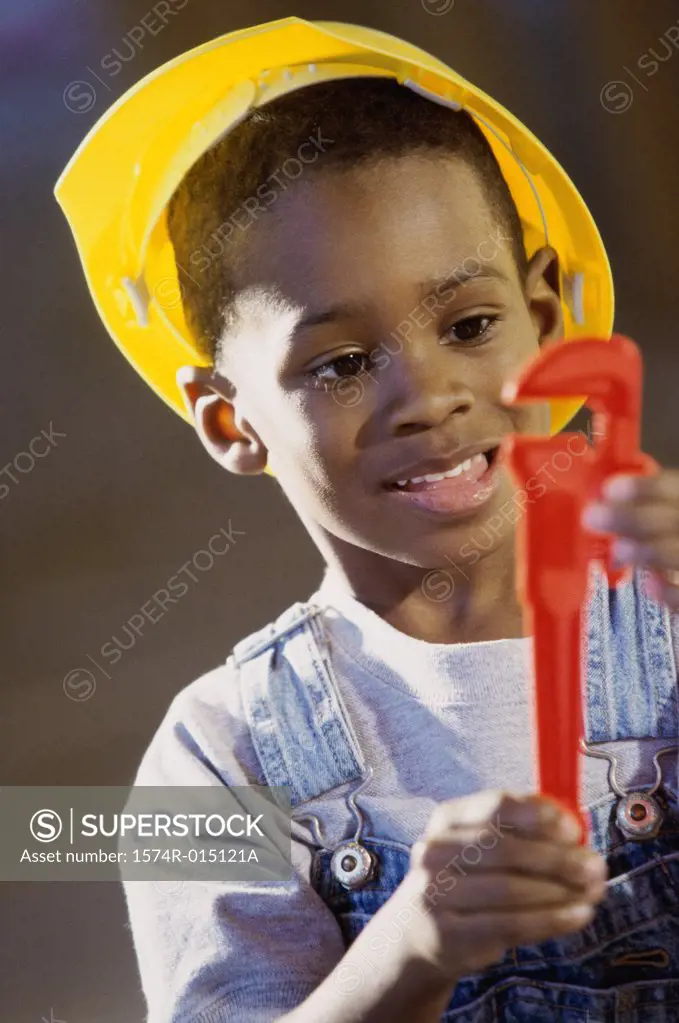 Close-up of a boy dressed as a construction worker holding a toy pipe wrench