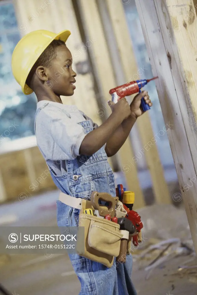 Side profile of a boy dressed as a construction worker holding a toy drill