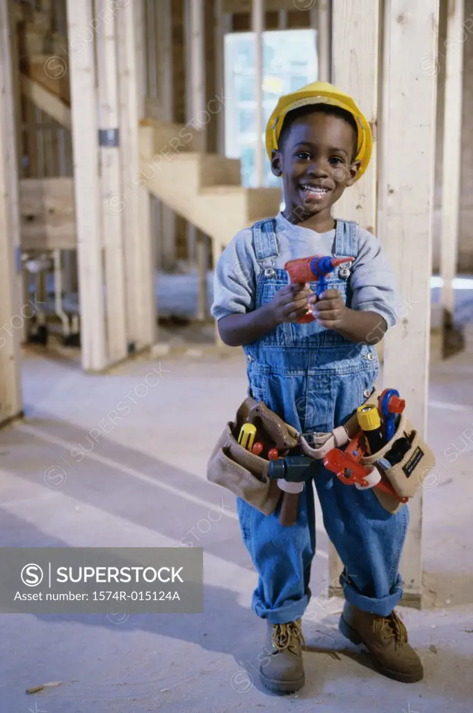 Portrait of a boy dressed as a construction worker holding a toy drill