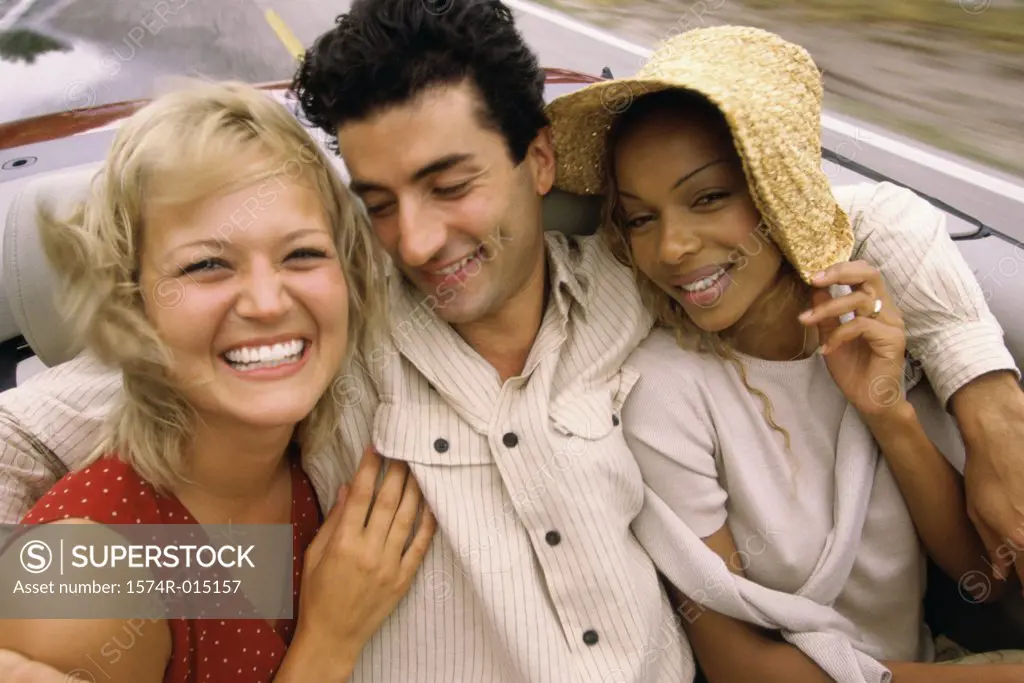 Close-up of a young man and two young women sitting in a car