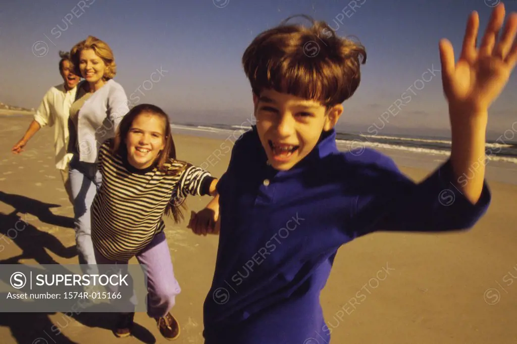 Parents and their two children running on the beach