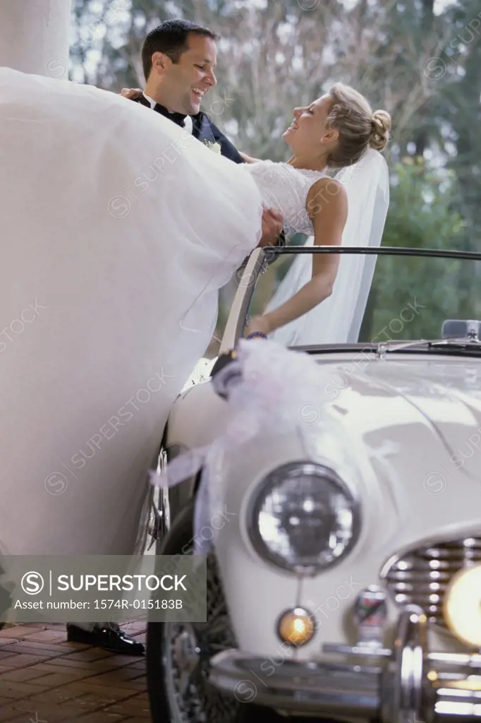 Groom carrying his bride out of a car