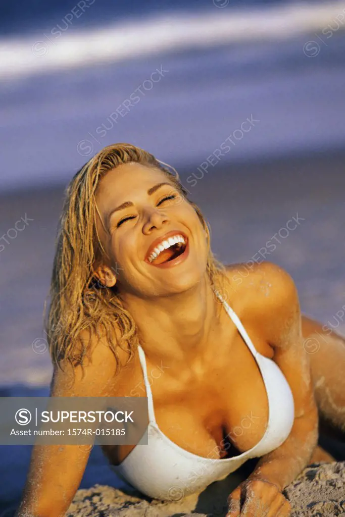 Close-up of a young woman laughing on the beach with her eyes closed