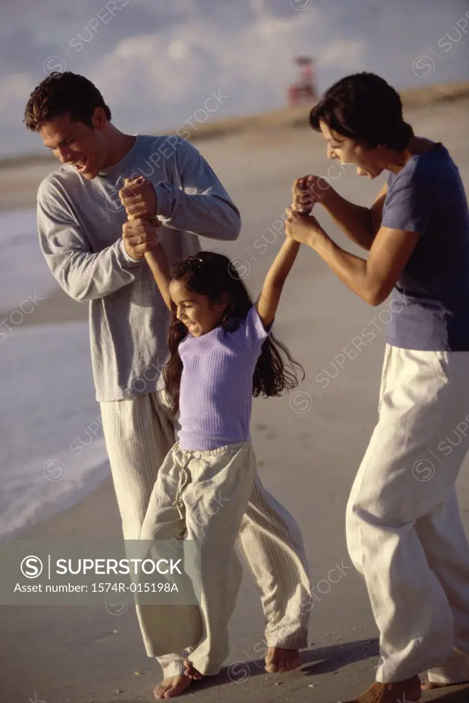 Parents swinging their daughter on the beach