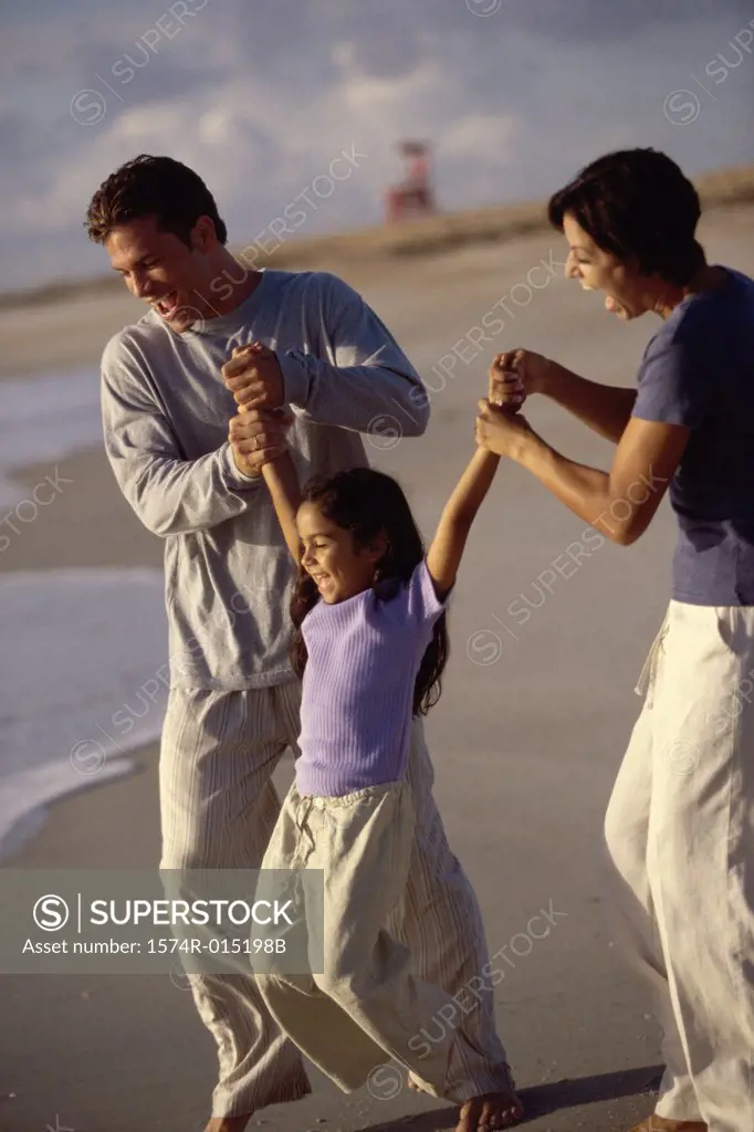 Parents swinging their daughter on the beach