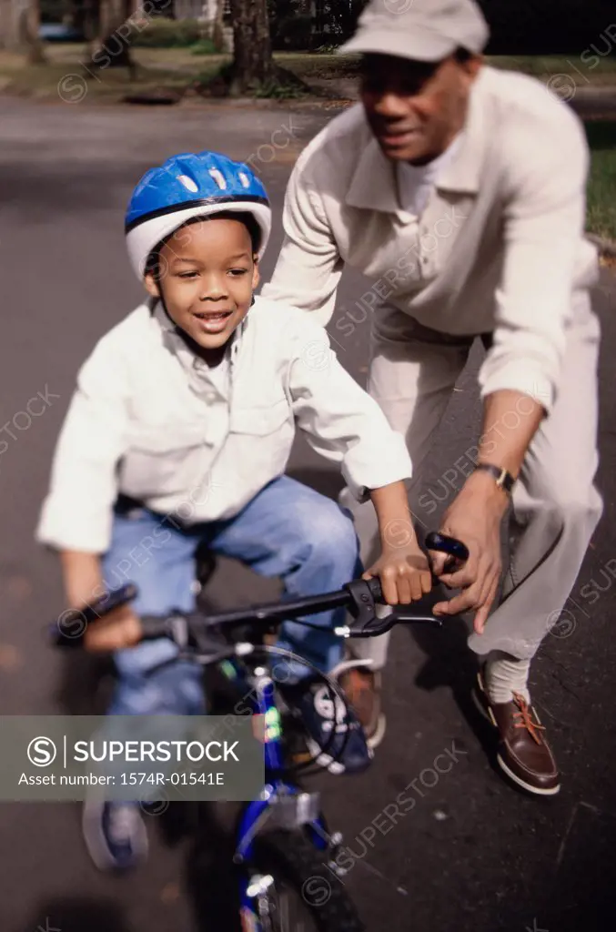 Grandfather helping his grandson ride a bicycle