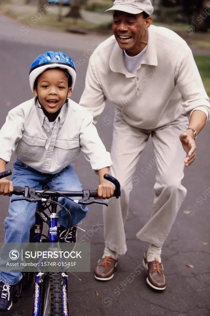 Grandfather helping his grandson ride a bicycle