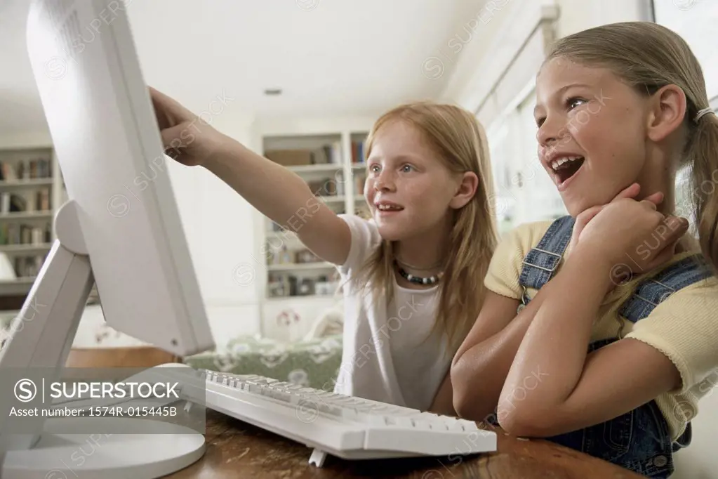 Close-up of two girls pointing to a computer monitor