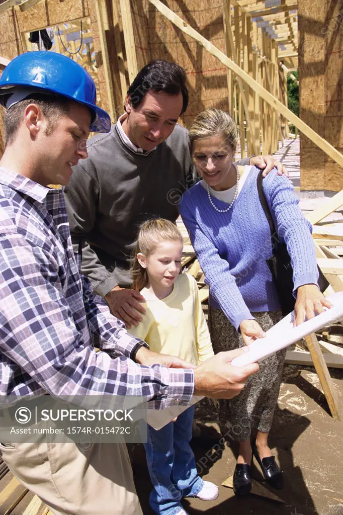 Family standing at a construction site with a worker holding blueprints