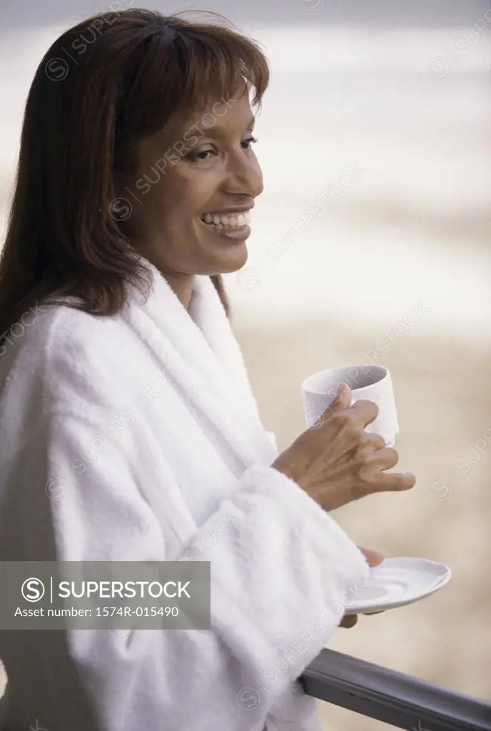 Side profile of a mid adult woman holding a cup of coffee smiling