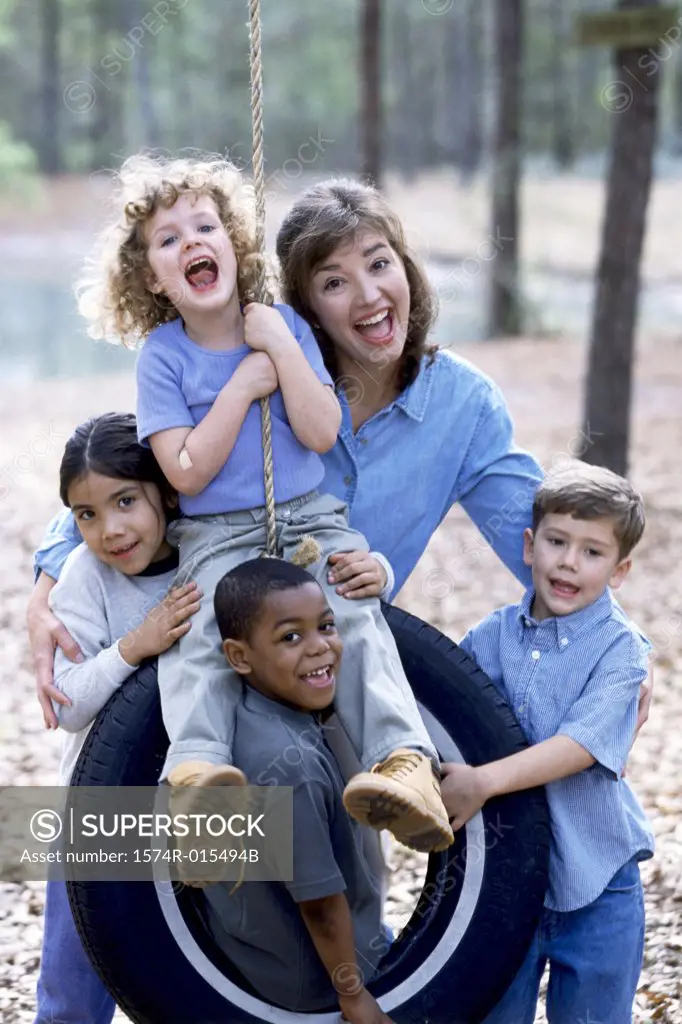 Portrait of a young woman with four children screaming on a tire swing