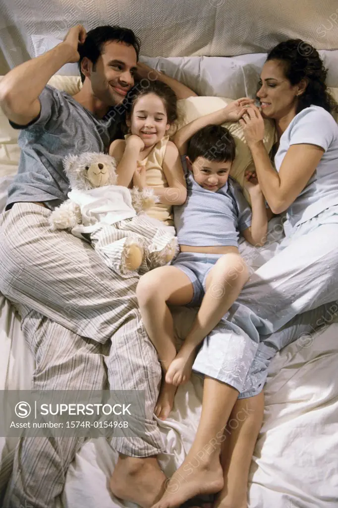 High angle view of parents lying on a bed with their son and daughter