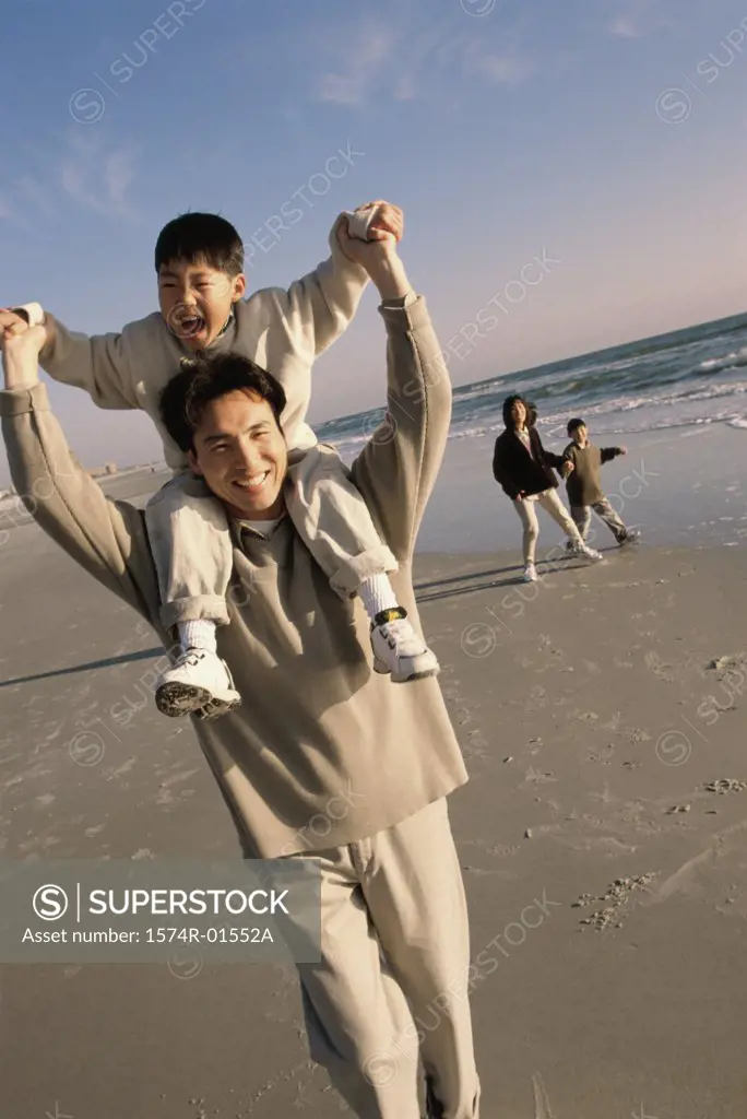 Man carrying his son on his shoulders at the beach