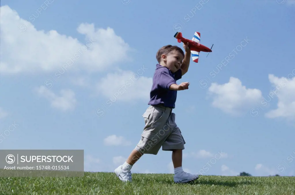 Side profile of a boy playing with a toy airplane
