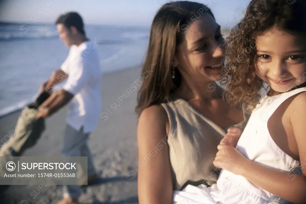Close-up of a mother carrying her daughter on the beach