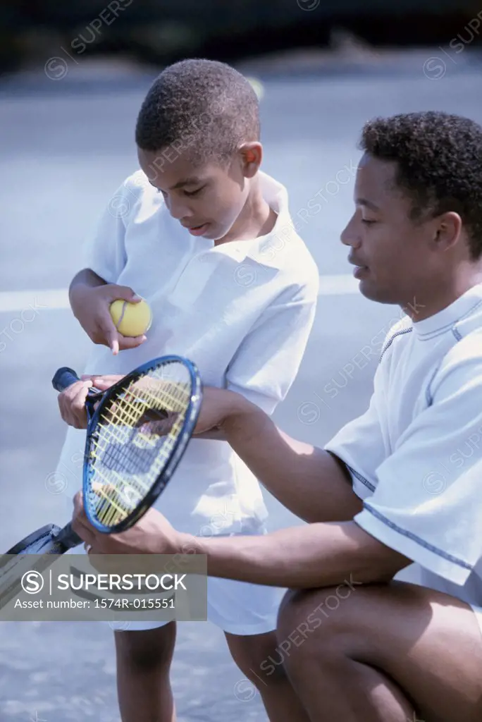 Side profile of a father teaching his son to play tennis