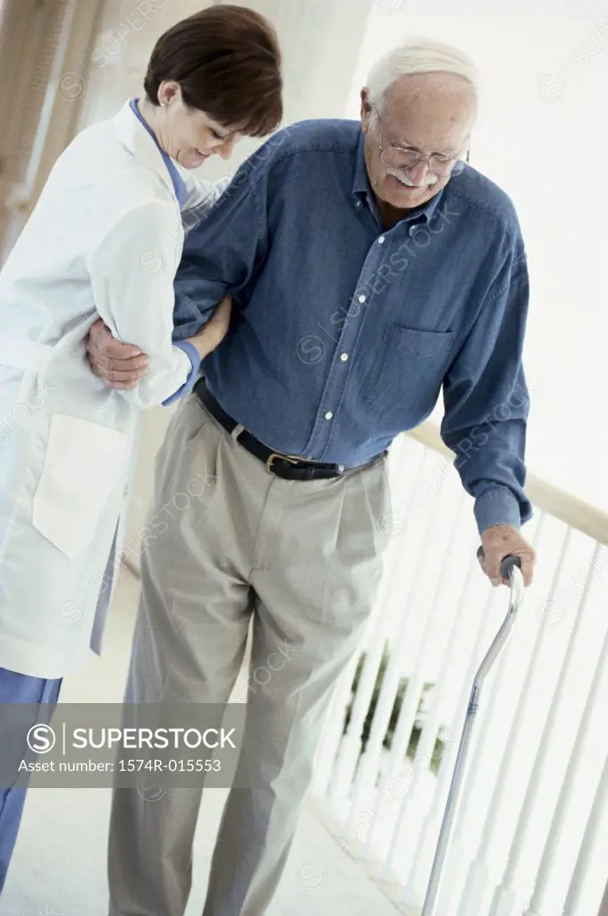 Side profile of a female doctor helping a patient to walk with a cane