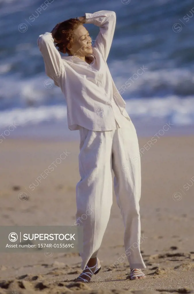 Senior woman standing with her hands behind her head on the beach