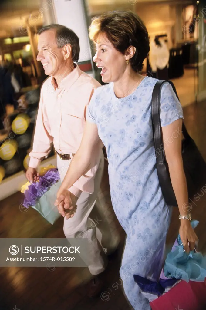 Mid adult couple holding shopping bags walking on a road