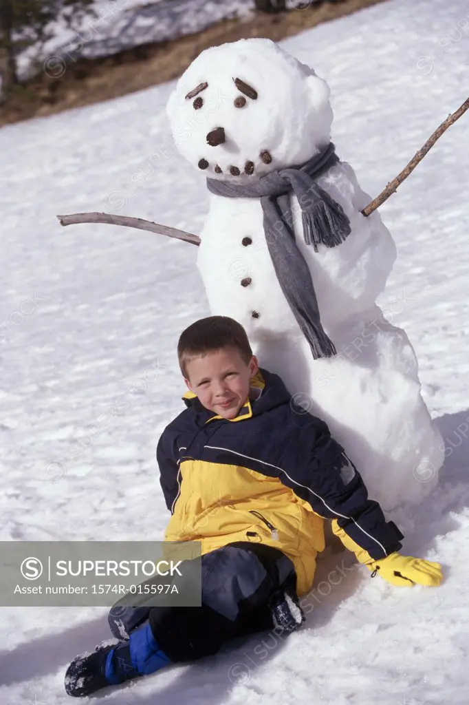 Portrait of a boy sitting in front of a snowman