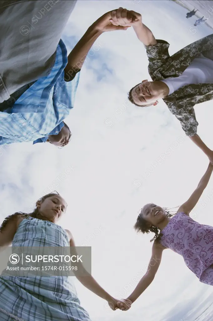 Low angle view of two boys and two girls holding hands