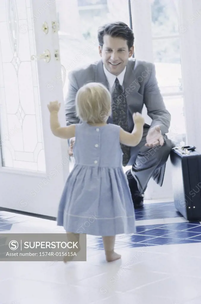 Rear view of girl greeting her father at the front door