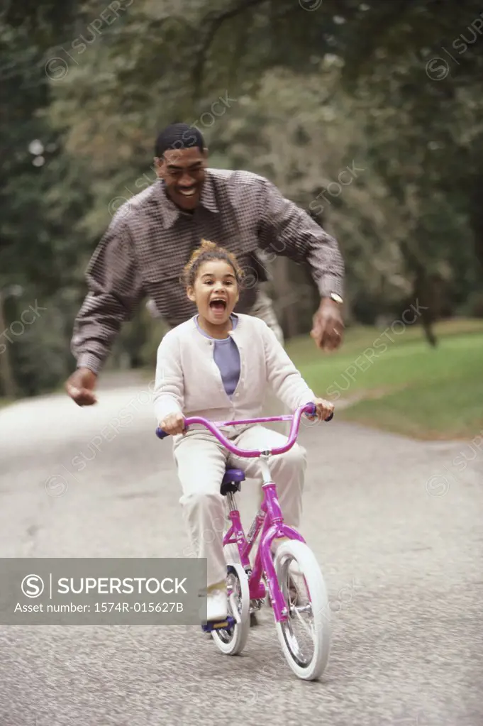 Father helping his daughter ride a bicycle