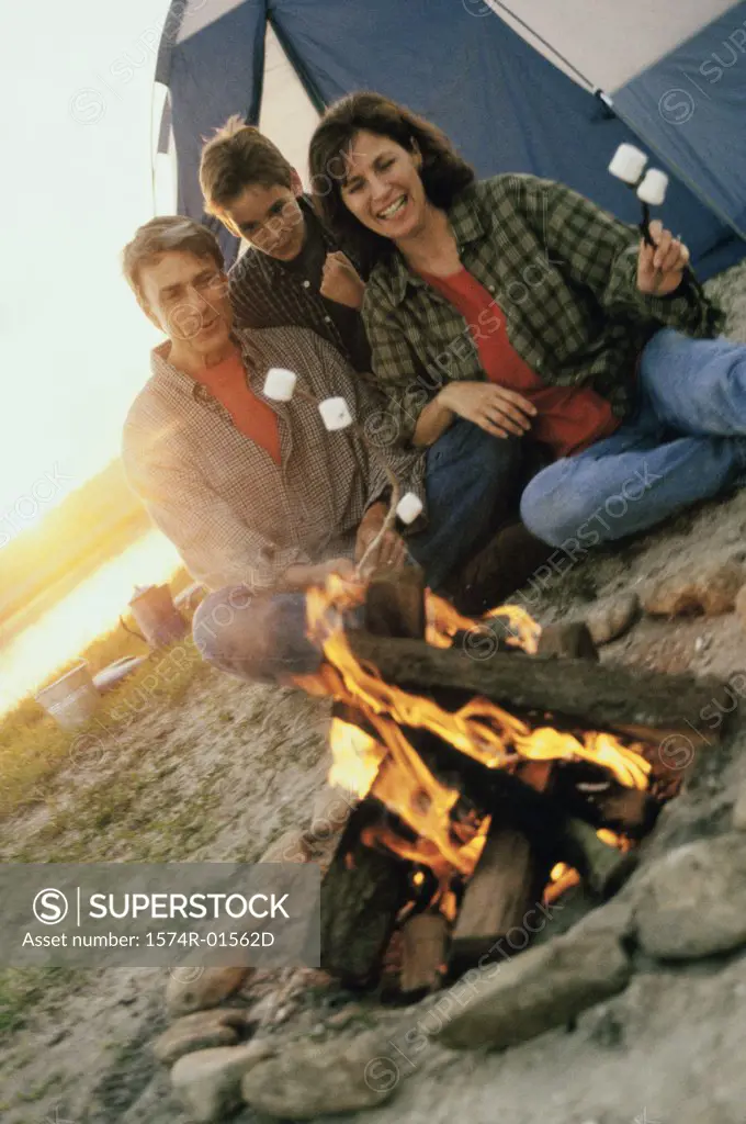 Parents with their son sitting in front of a campfire on the beach