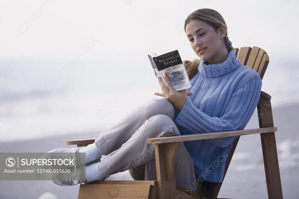 Close-up of a young woman reading a book on the beach