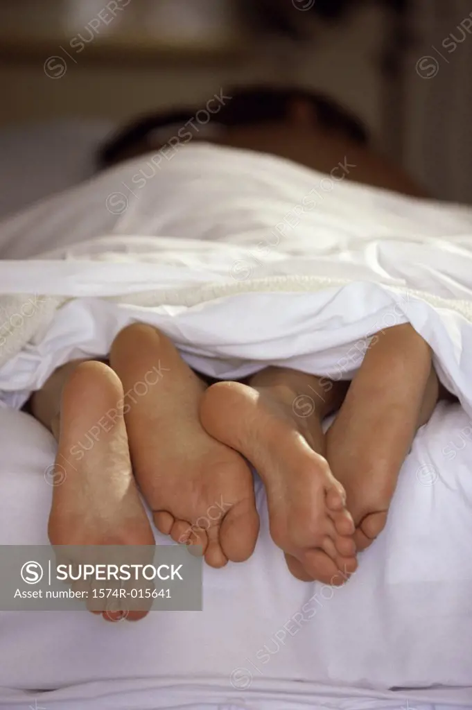 Feet of a couple lying in a bed