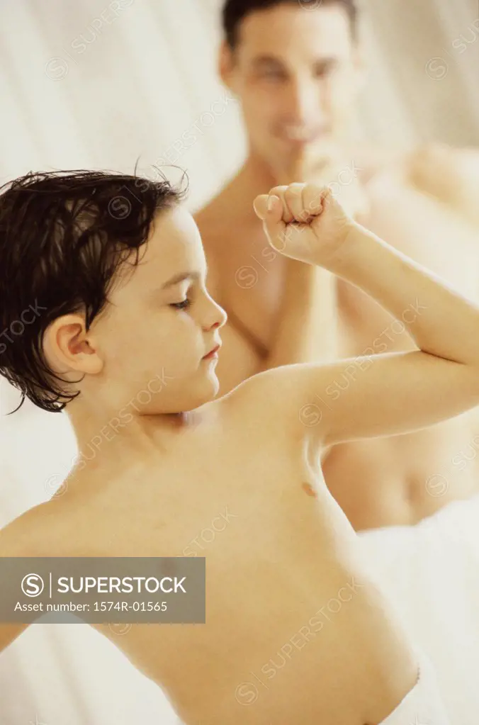 Close-up of a boy flexing his muscles for his father