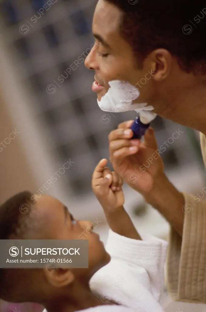Close-up of a boy watching his father shave