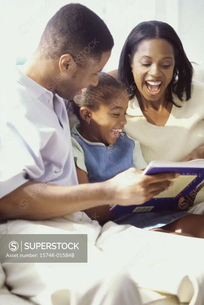 Parents reading a book with their daughter