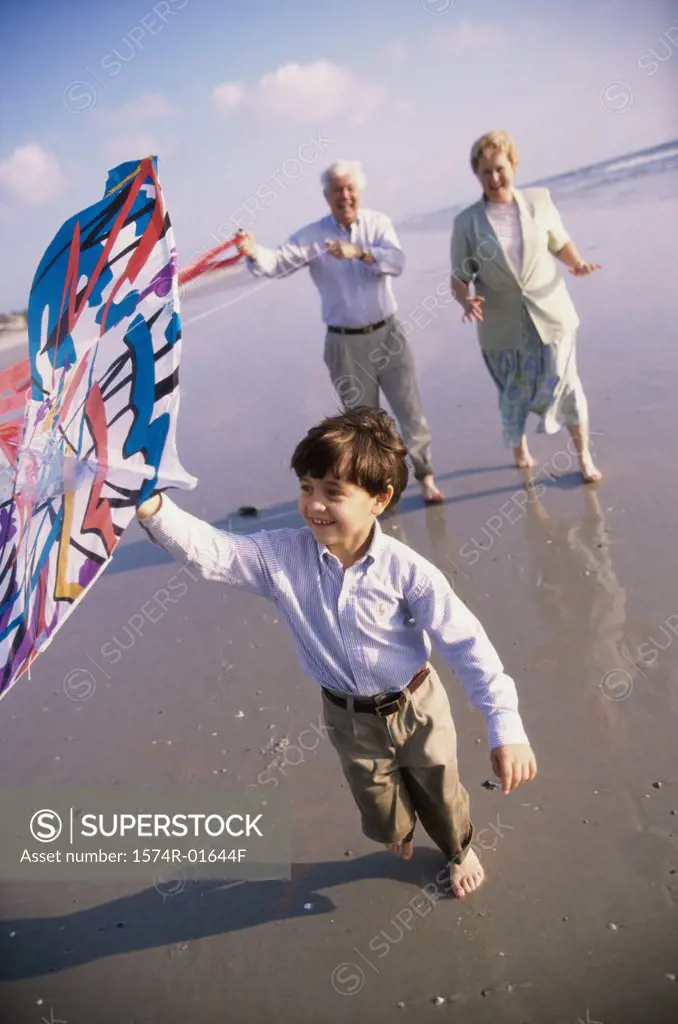Grandson flying a kite at the beach with his grandparents