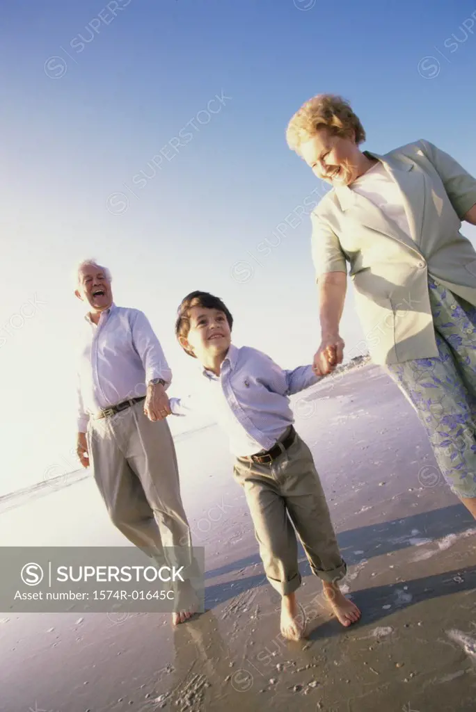 Grandson running at the beach with his grandparents