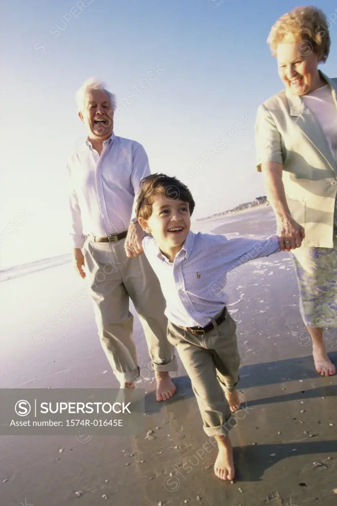 Grandson running at the beach with his grandparents