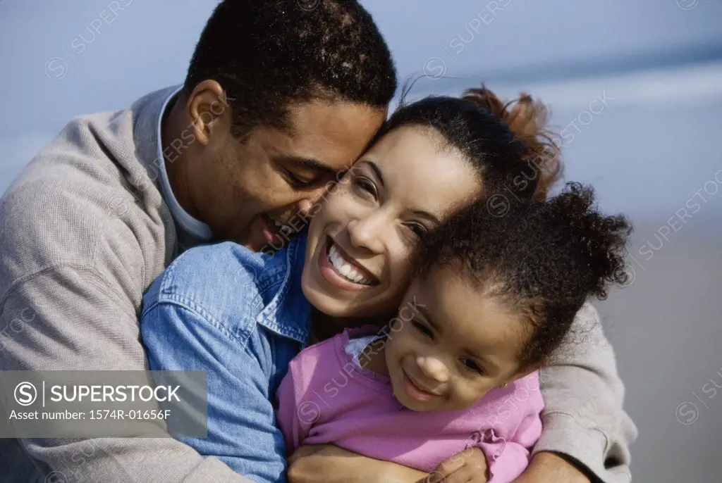 Close-up of parents hugging their daughter