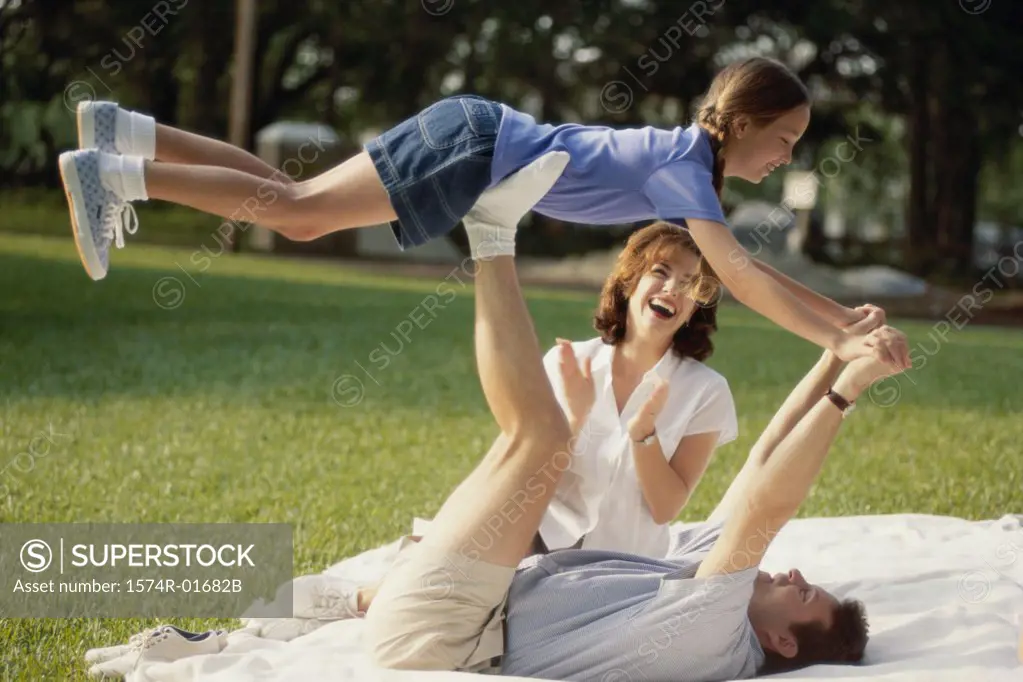 Father and mother playing with their daughter on a lawn