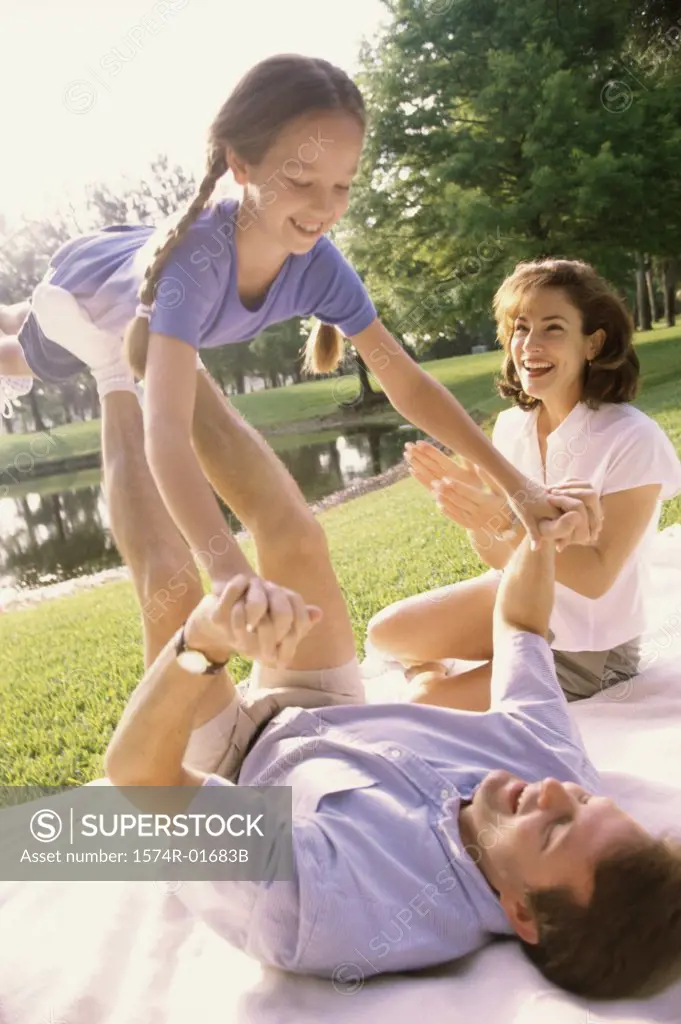 Father and mother playing with their daughter on a lawn