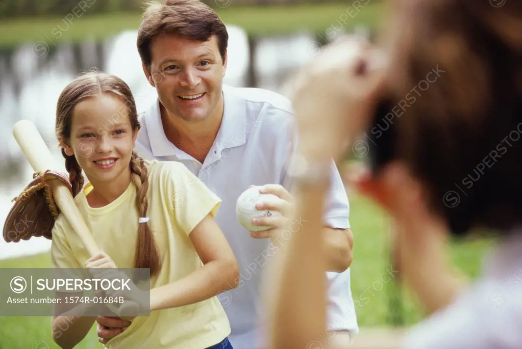Father holding a baseball bat standing with his daughter