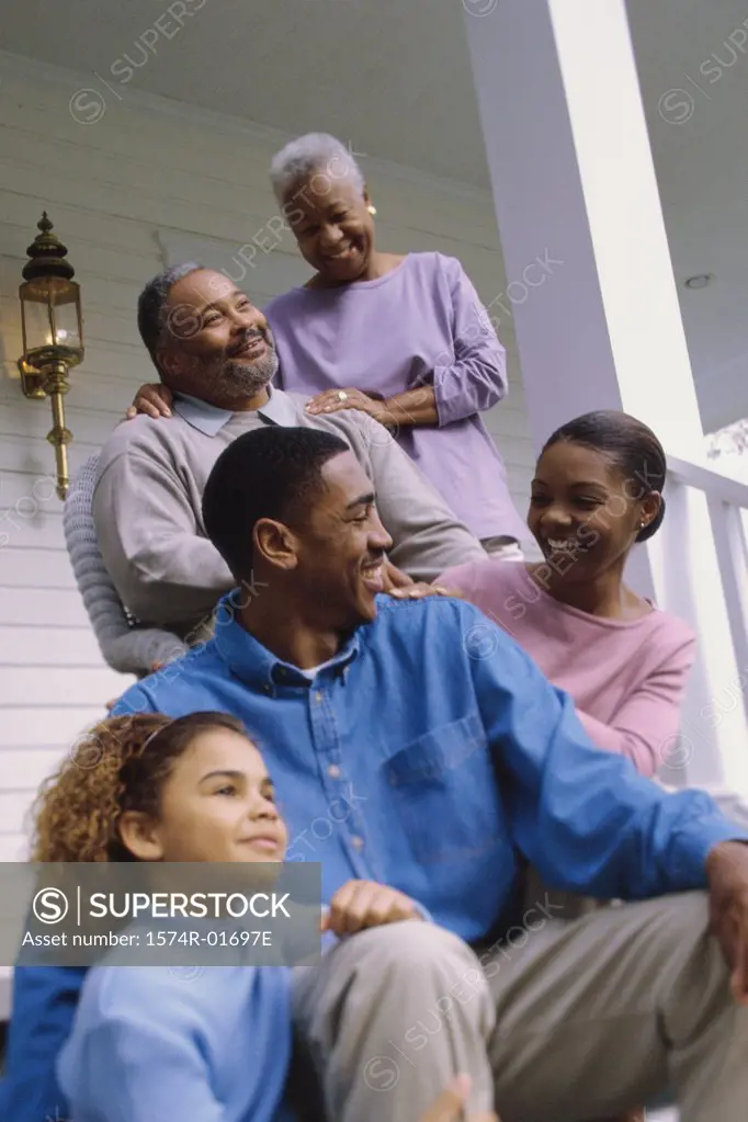 Grandparents sitting on the front porch with their son and granddaughter