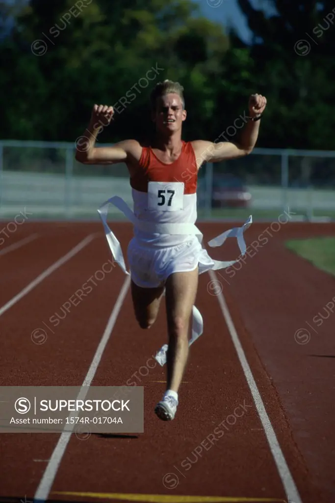 Portrait of a male runner crossing the finishing line with his arms raised